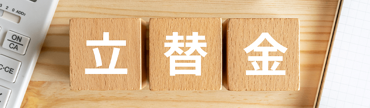木製ブロックに「立替金」と書かれ、周囲に電卓とノートが見えるイメージ画像