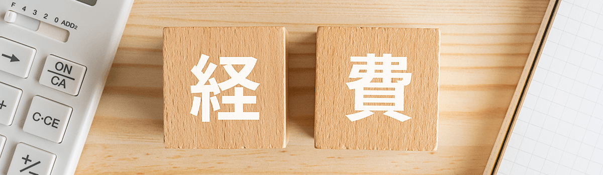 木製ブロックに「経費」と書かれ、周囲に電卓とノートが見えるイメージ画像